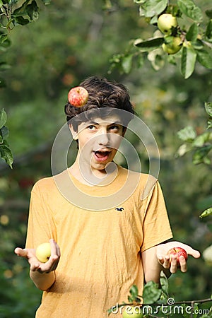 Happy boy juggling apples smile wink on apple tree green garden background Stock Photo