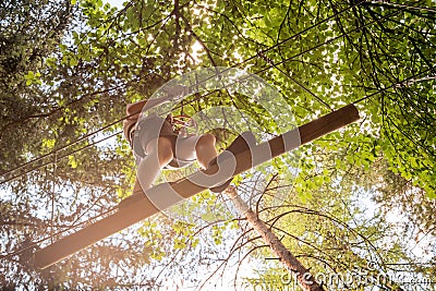 Teenager having fun on high ropes course, adventure, park, climbing trees in a forest in summer Stock Photo