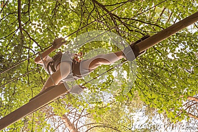 Teenager having fun on high ropes course, adventure, park, climbing trees in a forest Stock Photo