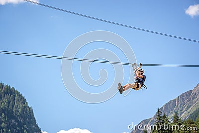 Teenager having fun on a zip line in the Alps, adventure, climbing, via ferrata during vacations in summer Stock Photo