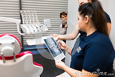 Teenager is hiding peeking out of the wall as dentists look at his x-ray..Boy still does not understand the seriousness of the hea Stock Photo