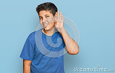 Teenager hispanic boy wearing casual clothes smiling with hand over ear listening an hearing to rumor or gossip Stock Photo