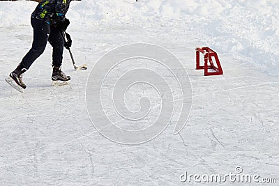 Teenager with hockey stick, wearing ice-skating, skates with puck, plans to shoot at little training red goal Active sport outdoor Stock Photo