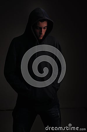 Teenager with hoodie looking down on black background Stock Photo