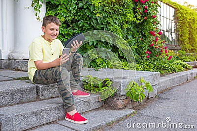 A teenager in the open with a phone in his hands connects a music column on bluetooth Stock Photo