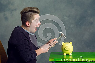 Teenager open piggybank with hammer Stock Photo