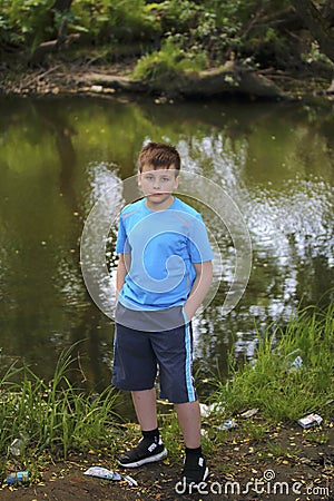 A teenager poses for a photographer while walking in a park by the river. Stock Photo