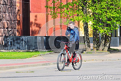 Teenager Riding Bicycle While on the Phone Editorial Stock Photo