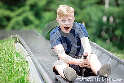 Teenager riding at bobsled roller coaster rail track Stock Photo