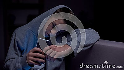 Teenager scrolling phone in darkness, threats from internet, gadget addiction Stock Photo