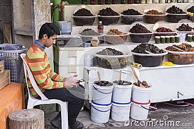 Teenager seller assistant looking his mobile phone Editorial Stock Photo