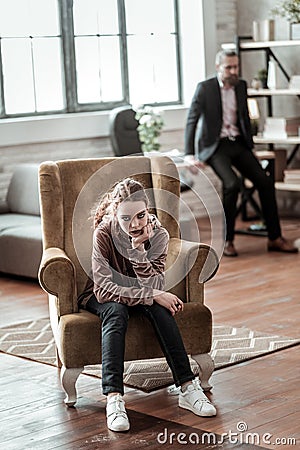 Teenager sitting in armchair feeling awful after argument Stock Photo