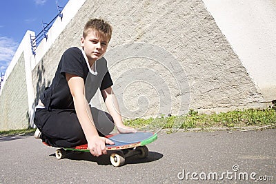 A teenager with a skateboard. Sits on a skateboard. Stock Photo