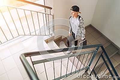 Teenager skateboarder boy with a skateboard going up by staircase home. Youth generation Freetime spending concept image Stock Photo