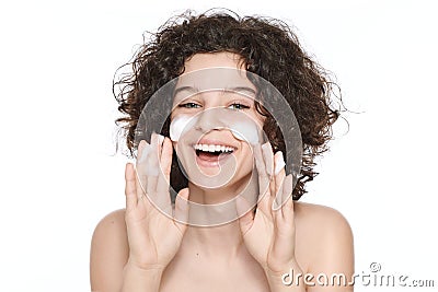 Teenager skincare. Beautiful teenage girl with gorgeous curly hair and green eyes using foaming cleanser. Face washing concept. Stock Photo