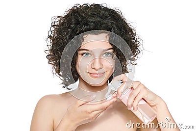 Teenager skincare. Beautiful teenage girl with gorgeous curly hair and green eyes using foaming cleanser. Face washing concept. Stock Photo