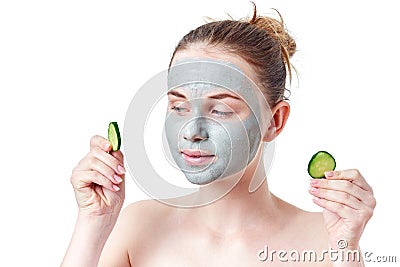 Teenager skincare concept. Young teen girl with dry clay facial mask holding two slices of cucumber Stock Photo