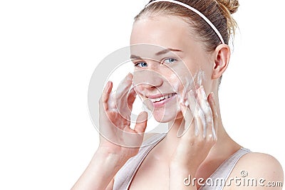 Teenager skincare. Smiling beautiful redhead teen girl with freckles and blue eyes using foaming cleanser. Stock Photo