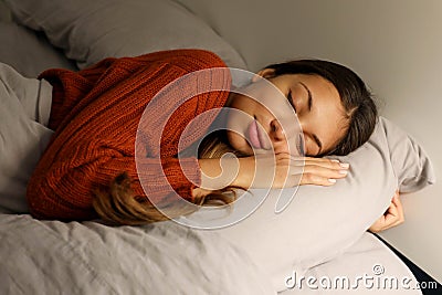 Teenager sleeps hugging pillow on bed at night Stock Photo