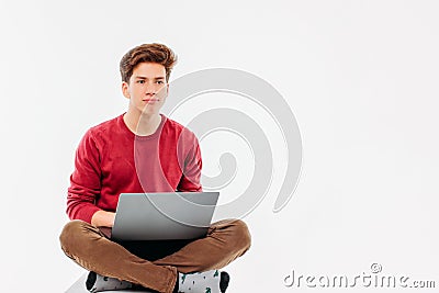 Teenager student with funny face working at laptop on white background Stock Photo