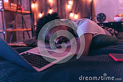 Teenager tired of having fun all day and falling asleep right next to laptop. Stock Photo