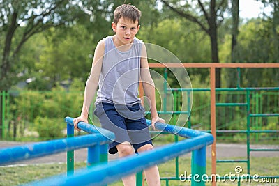 The teenager in a vest is engaged on uneven bars Stock Photo