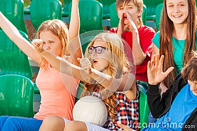 Teenagers cheer for team during game at stadium Stock Photo