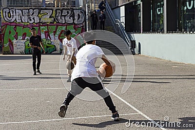 Teenagers play street basketball or streetball. Sports, healthy lifestyle and team games in the street of Barcelona Editorial Stock Photo