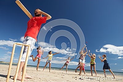 Teenagers playing cricket on beach Stock Photo