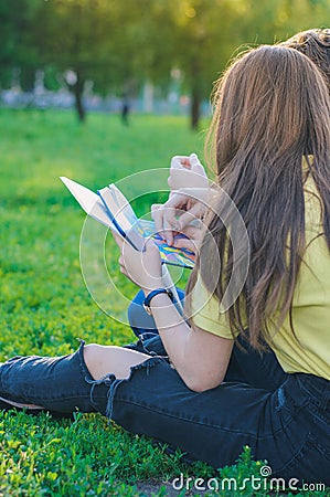 Teenagers studying together and lerning notes on the green lawn near college Stock Photo