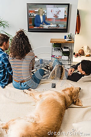 teens watching news and dog lying on bed Stock Photo