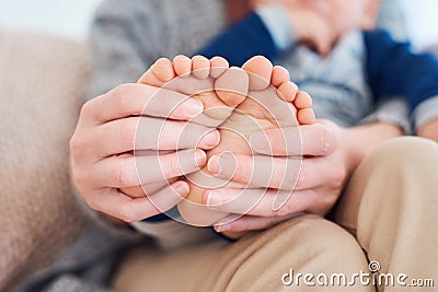 Teeny tiny little toes. Closeup shot of a mother holding her little baby boys feet. Stock Photo