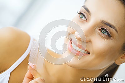 Teeth Whitening. Beautiful Smiling Woman Holding Whitening Strip Stock Photo