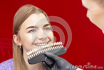 Teeth whitening procedure girl reception dentist for teeth whitening the doctor picks up the color of the teeth Stock Photo