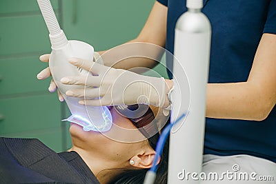 Teeth whitening procedure. Dentist stomatologist whitening teeth for patient in medicine dental clinic with lamp Stock Photo
