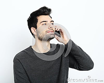 Tehnology, emotion and people concept: Smiling young man talking by smartphone Stock Photo