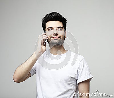 Tehnology, emotion and people concept: Smiling young man talking by smartphone Stock Photo