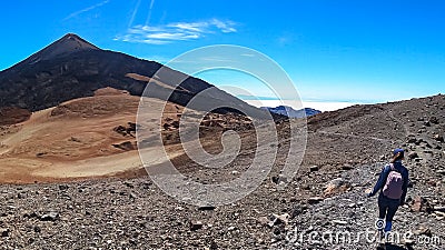 Teide - Woman with backpack on volcanic desert terrain hiking trail leading to summit volcano Pico Viejo, Tenerife, Spain. Stock Photo