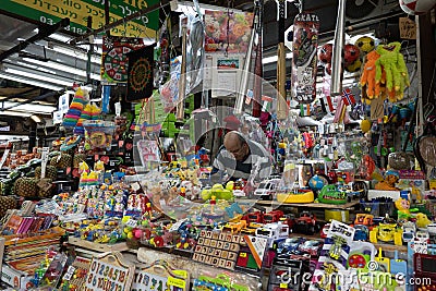 Vendor immersed in his toy stall at a lively Israeli market, surrounded by a vibrant array of toys and games Editorial Stock Photo