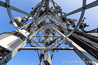 Telecommunication tower with microwave equipment, radio panel antennas, outdoor remote radio units, power cables Stock Photo