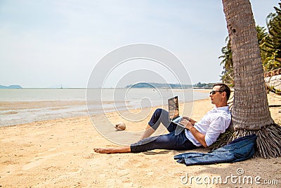 Telecommuting, businessman relaxing on the beach with laptop and palm, freelancer workplace, dream job. Stock Photo