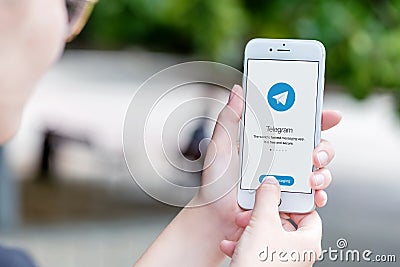 Telegram messenger on Apple iPhone in female hands over the shoulder view Editorial Stock Photo