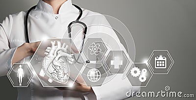 Unrecognizable female doctor holding graphic virtual visualization model of Heart organ in hands. Multiple medical icons on the Stock Photo