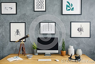 Telescope and desktop computer on wooden desk in grey workspace Stock Photo