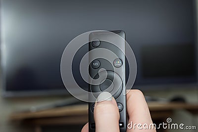 Television remote control changes channels thumb on the blue TV screen Stock Photo