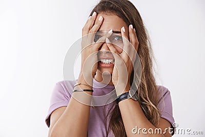 Tell when horror over. Portrait scared insecure cute timid girlfriend hiding face cover hands peeking through fingers Stock Photo