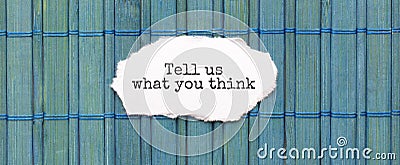 TELL US WHAT YOU THINK text on the piece of paper on the green wood background Stock Photo