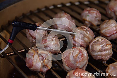 Temperature probe measuring inside temp from meatballs with bacon on BBQ Stock Photo