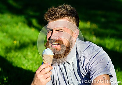 Temptation concept. Bearded man ice cream cone. Man with long beard eats ice cream, while sits on grass. Man with beard Stock Photo