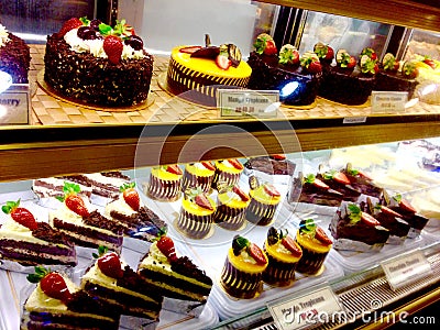 Tempting bakery fancy sweet chocolate cakes desserts mango cheesecake & fresh strawberries Stock Photo